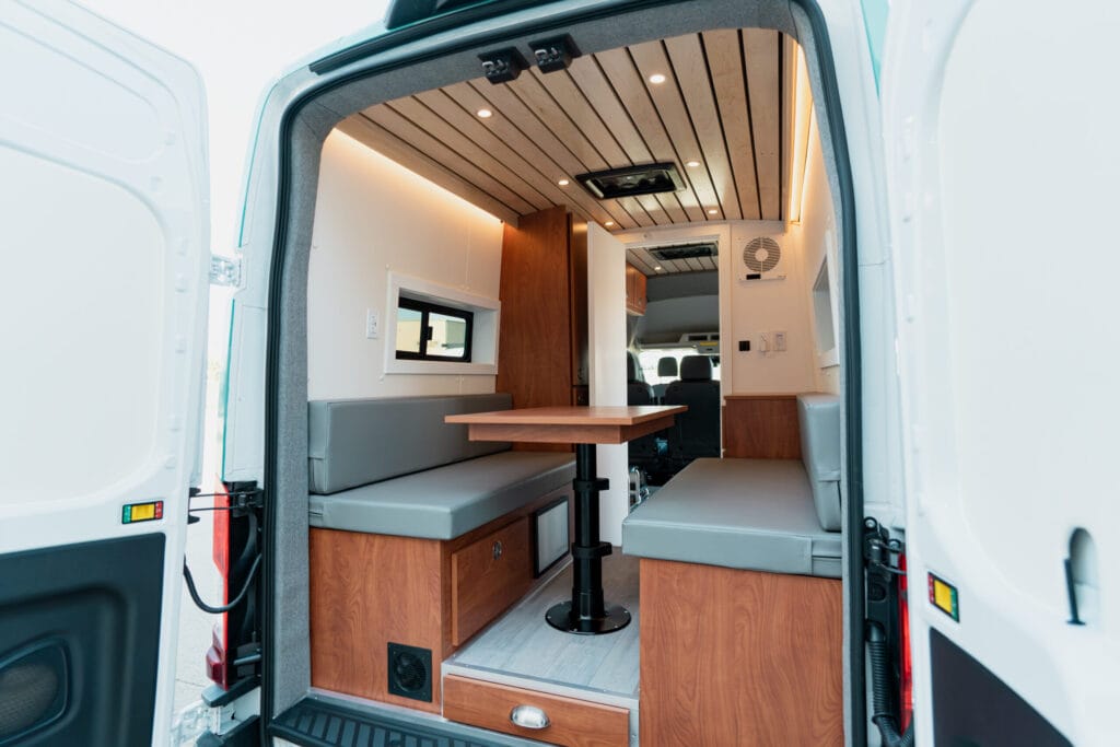 Rear seating area inside Phoebe with two benches, a table and wood cabinetry